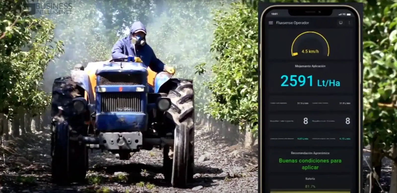Tractor con nebulizadora aplicando en un huerto, junto al celular del operador que muestra el mojamiento por hectárea